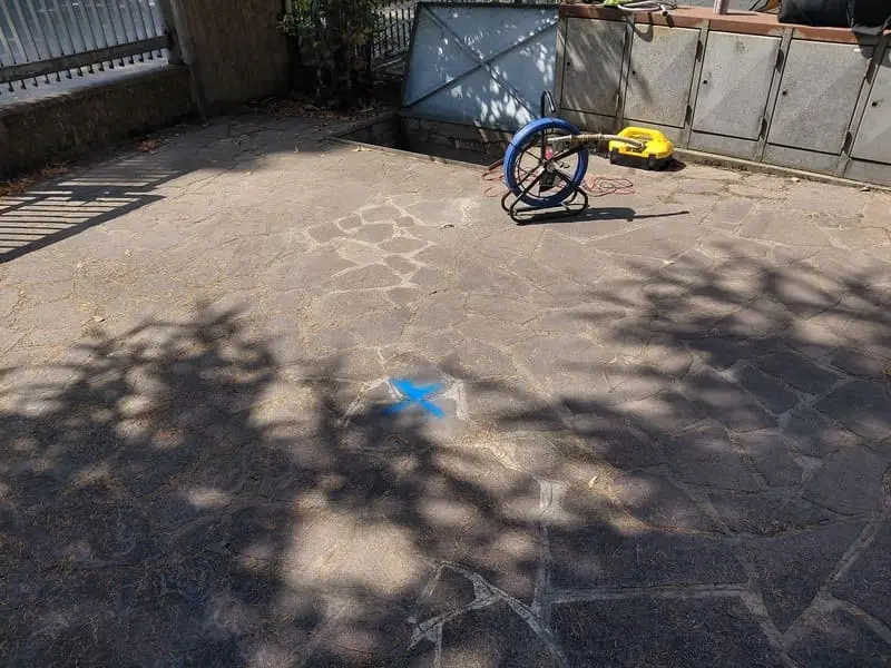 Punto di una perdita d'acqua occulta segnato con vernice blu, individuato con estrema precisione grazie a sonda geofonica e localizzatore di tubi interrati.